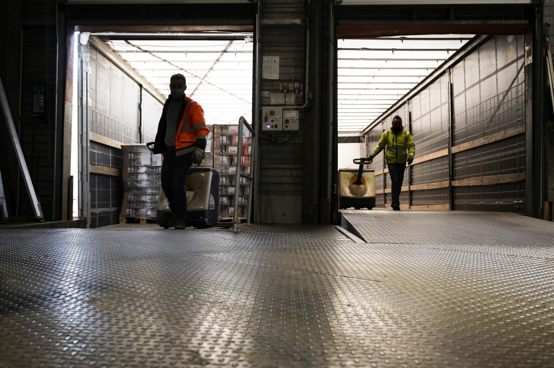 Livreurs chargeant des palettes dans des camions