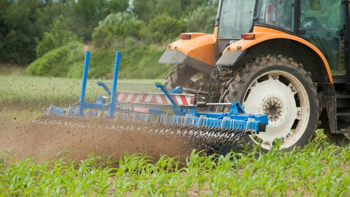 Retournement de la terre par une herse tirée par un tracteur