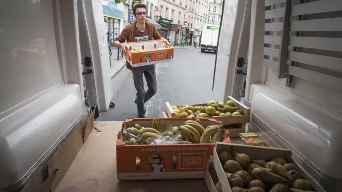 Homme portant un cageot de bananes et s’apprêtant à le stocker dans une camionnette