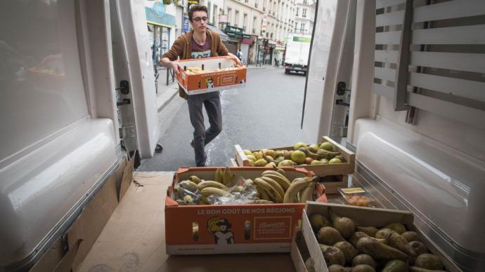 Homme portant un cageot de bananes et s’apprêtant à le stocker dans une camionnette