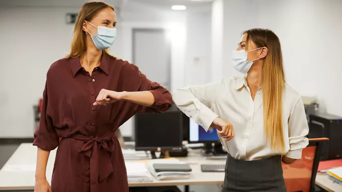 collègues qui se saluent en respectant les gèstes barrière 